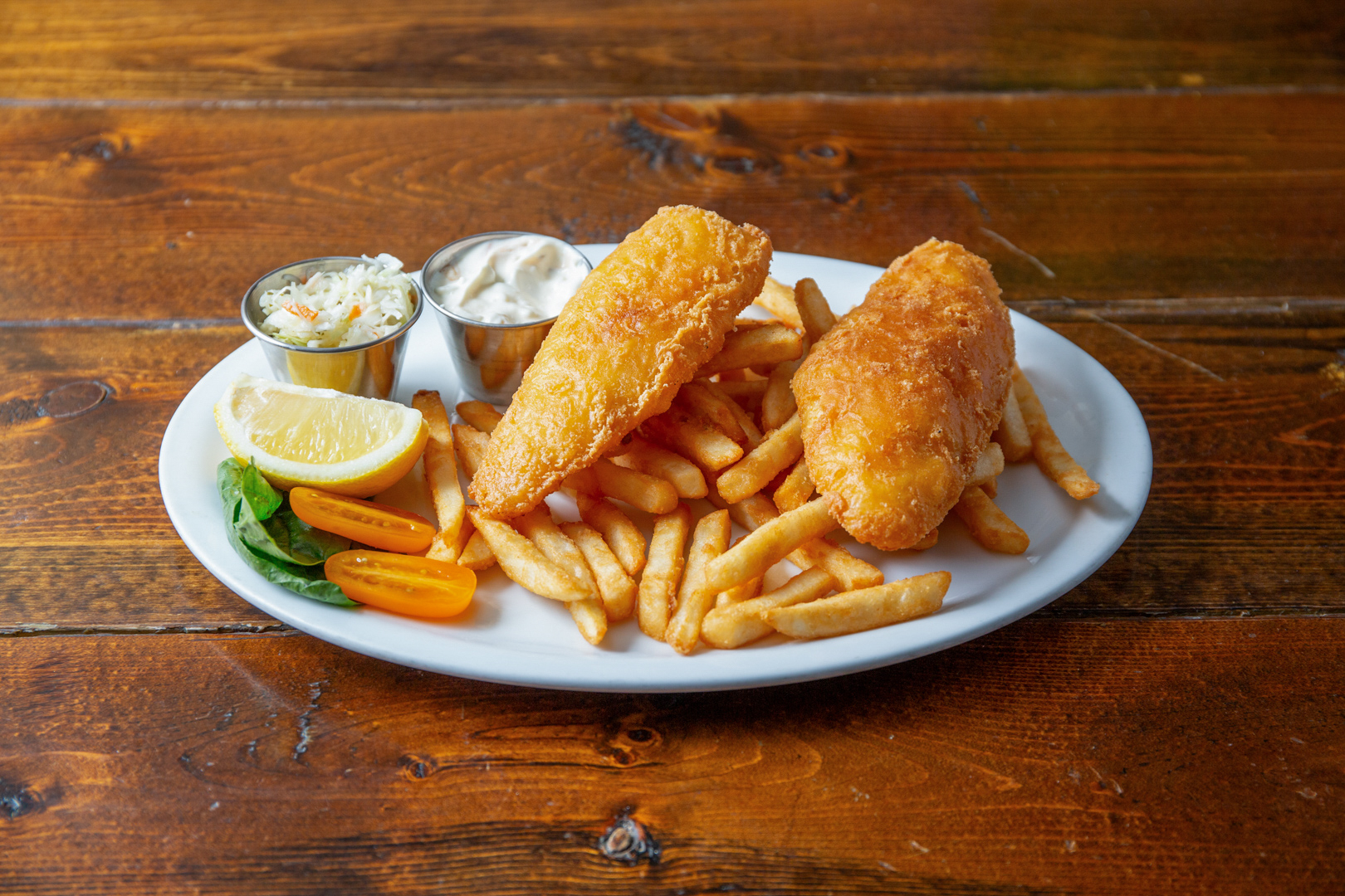 Fish and chips with fries, tangy sauce, slaw, and garnish